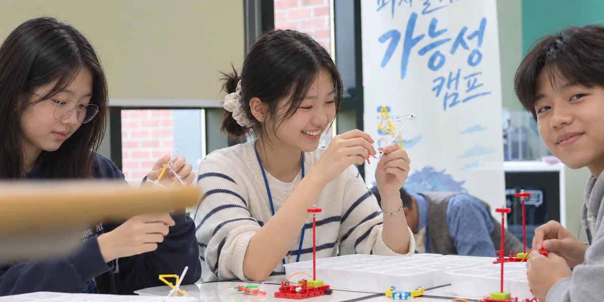 피지컬 AI 가능성 캠프에서 부품으로 구조물을 만들며 웃고 있는 학생들